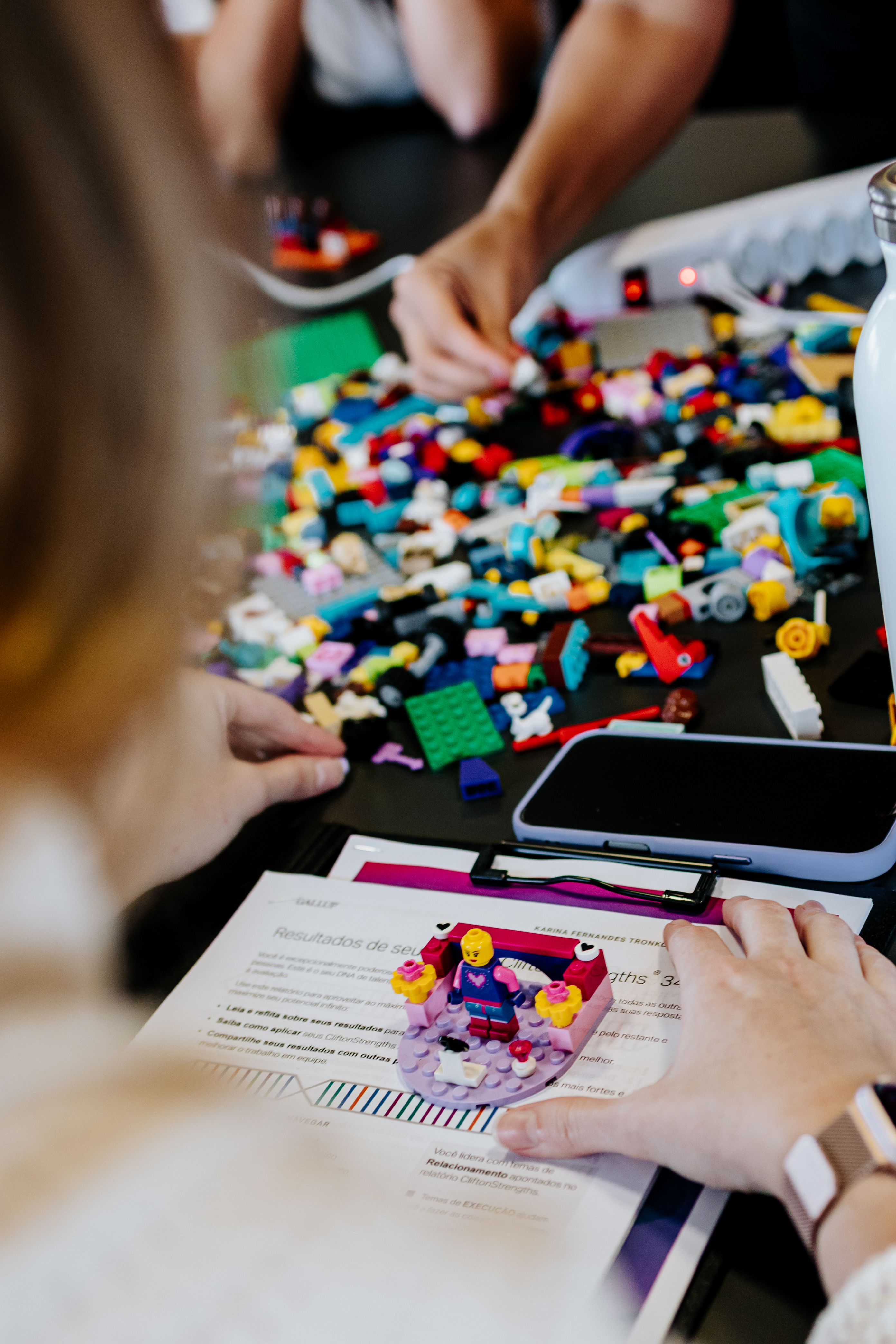 Mesa com diversas construções de LEGO® Serious Play® feitas por líderes do Sicredi, incluindo torres coloridas e figuras representando desafios de liderança.